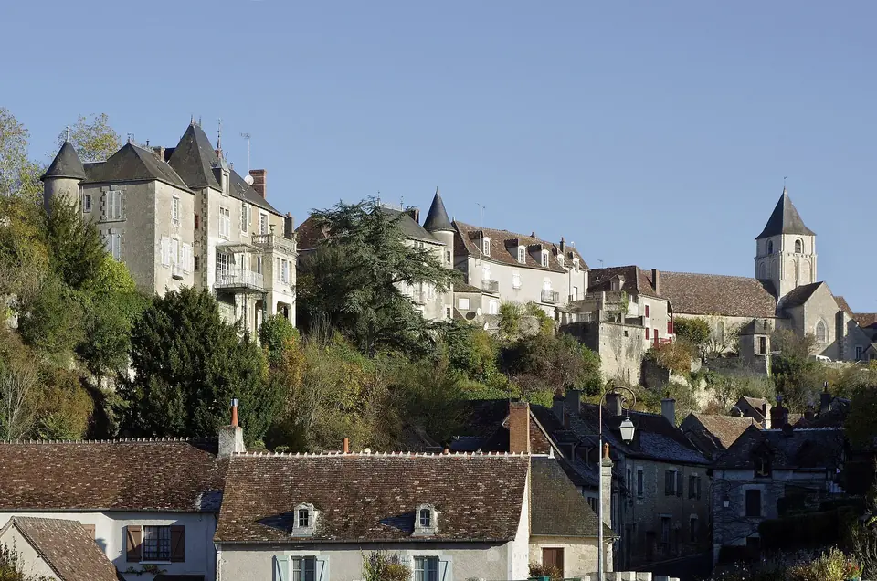 Maisons en pierre et tourelles d'Angles-sur-l'Anglin étagées sur le coteau, avec toits d'ardoise et clocher en arrière-plan.